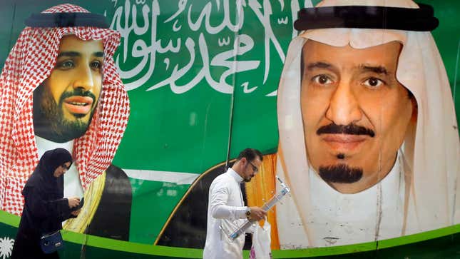 People walk past a banner showing Saudi King Salman, right, and his Crown Prince Mohammed bin Salman, outside a mall in Jiddah, Saudi Arabia.