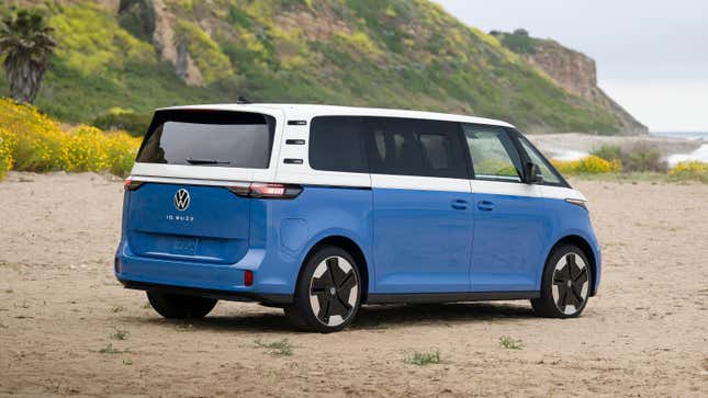 Rear 3/4 view of a blue and white Volkswagen ID Buzz on a beach