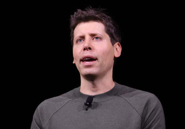 Close up of Sam Altman speaking, wearing a grey crewneck in front of a black background