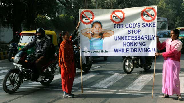 Two people hold up a sign asking people to stop honking their horns 