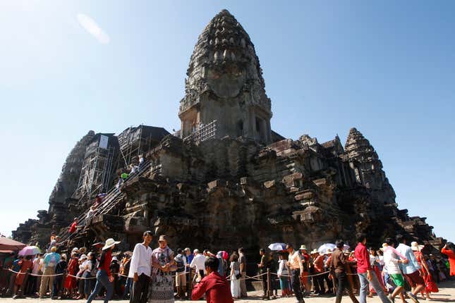 FILE -In this Sunday, Dec. 31, 2017, photo, tourists line up for stepping up Angkor Wat temple outside Siem Reap, Cambodia. Commercial operations have begum at Cambodia’s newest and biggest airport, designed to serve as an upgraded gateway to the country’s major tourist attraction, the centuries-old Angkor Wat temple complex in the northwestern province of Siem Reap. (AP Photo/Heng Sinith, File)