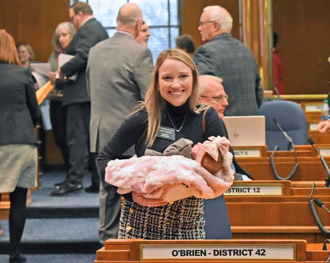 FILE - Rep. Emily O&#39;Brien R-Grand Forks carries daughter Jolene Green, 3 weeks, into the House chamber, Dec. 6, 2022, in Bismarck, N.D. Last year, the state representative helped persuade her colleagues to approve $66 million in child care spending proposed by Gov. Doug Burnum, a Republican. O&#39;Brien argued it could help the state&#39;s workforce shortage by helping more parents go to work. (Tom Stromme/The Bismarck Tribune via AP)