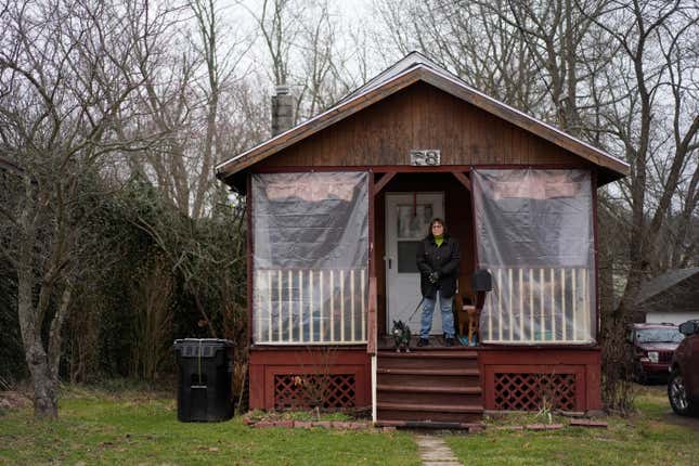 Marina Davis stands on her front porch with her dog Hunter in East Palestine, Ohio, on Tuesday, Jan. 30, 2024. Davis did not evacuate after the derailment and lives just outside the one-mile evacuation zone. Daily life largely returned to normal for residents of East Palestine, Ohio, months after a Norfolk Southern train derailed and spilled a cocktail of hazardous chemicals that caught fire a year ago, but the worries and fears are always there. (AP Photo/Carolyn Kaster)