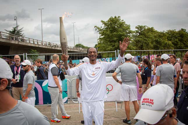 Rapper Snoop Dogg carries the Olympic flame during the last stage of the Olympic torch before the Olympic Games 2024 opening ceremony in Seine-Saint-Denis, France on July 26, 2024 