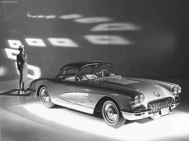 A black and white of a first-generation Chevrolet Corvette with a woman standing behind it