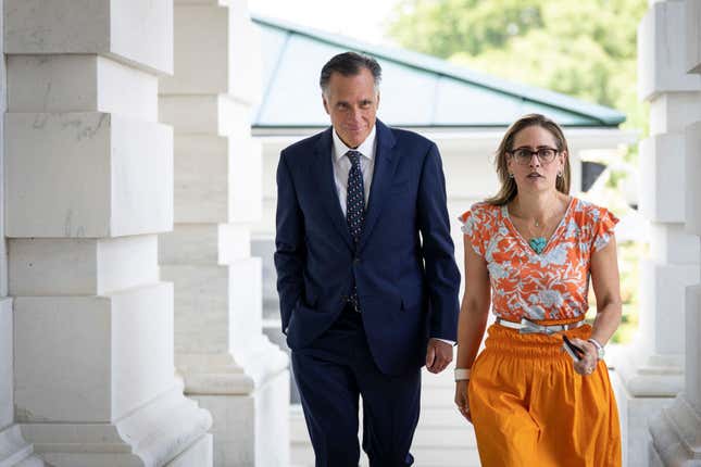  Sen. Mitt Romney (R-UT) and Sen. Kyrsten Sinema (D-AZ) walk together outside the U.S. Capitol on August 4, 2022, in Washington, DC. 