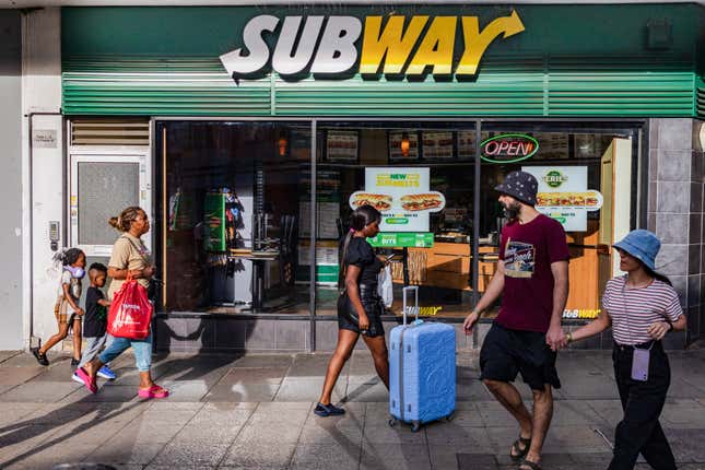 People walk past a Subway restaurant in London. 