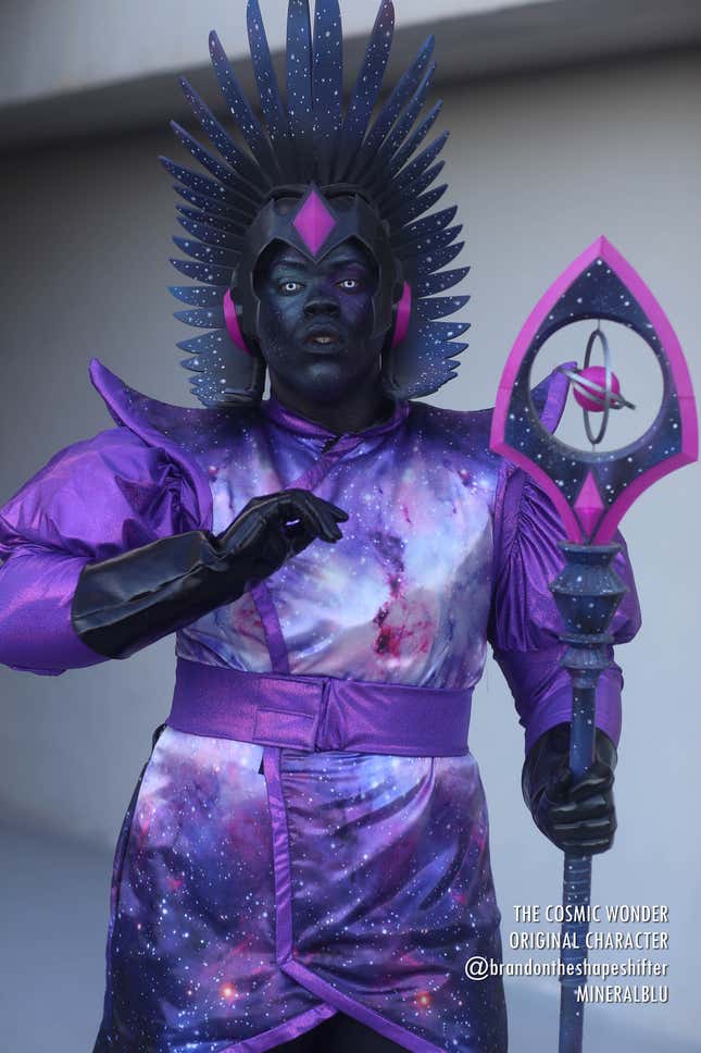 A cosplayer introduces their original character, The Cosmic Wonder, who is covered in galaxy-print designs and wields a staff.