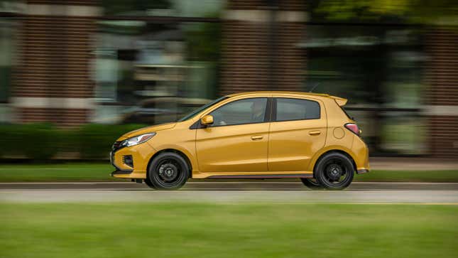 A dinky yellow Mitsubishi Mirage driving on a road 