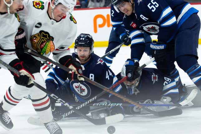 Jan 11, 2024; Winnipeg, Manitoba, CAN; Chicago Blackhawks forward Ryan Donato (8), Winnipeg Jets defenseman Josh Morrissey (44) and Winnipeg Jets forward Mark Scheifele (55) looks for the puck in front of Winnipeg Jets goalie Connor Hellebuyck (37) during the first period at Canada Life Centre.