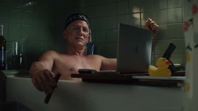 Daniel Craig sits in the bath, smoking a cigar, a laptop in front of him.
