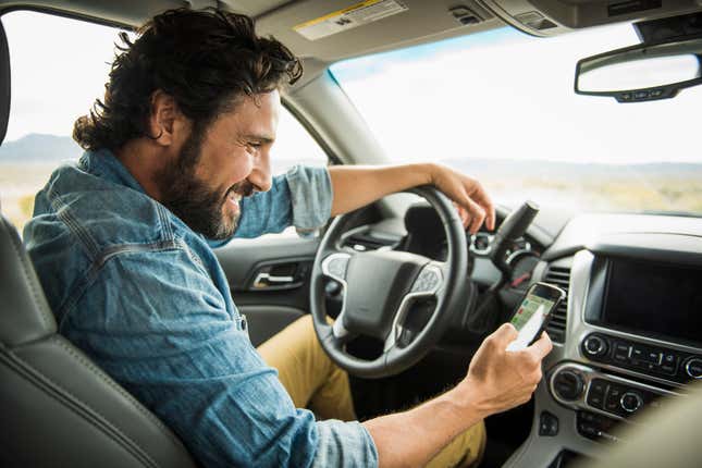 Man in denim shirt on phone while driving