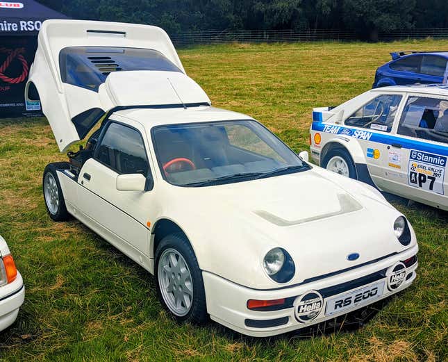 A white Ford RS200 with its engine cover open parked on a lawn