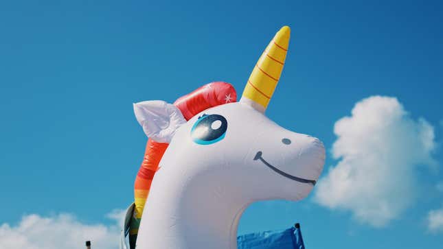 Inflatable plastic rubber unicorn against a blue sky.