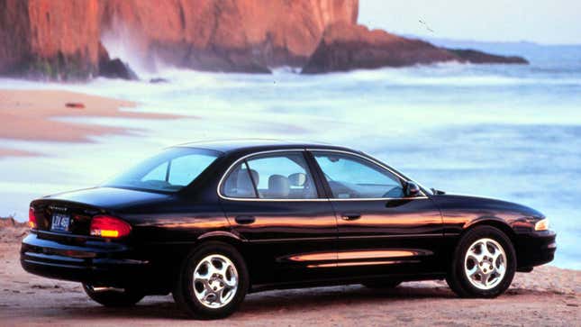 A photo of an Oldsmobile sedan parked on a cliff. 