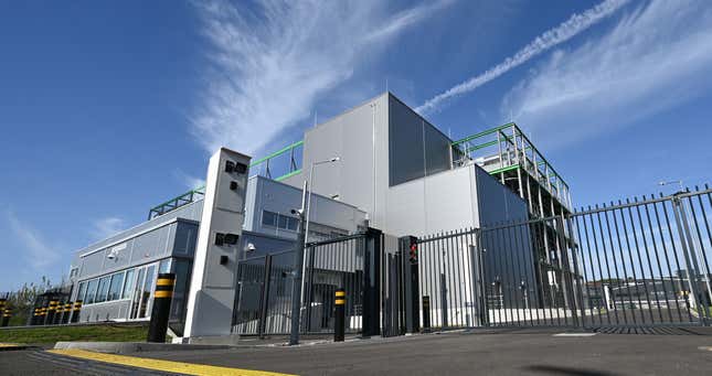 exterior view of a grey building partially behind a black gate