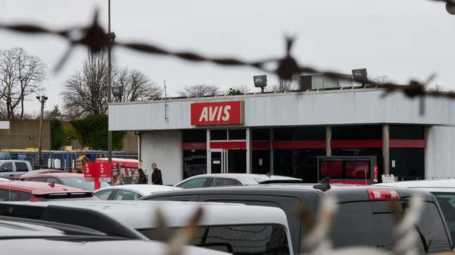 Un emplacement de location Avis vu à travers des barbelés.