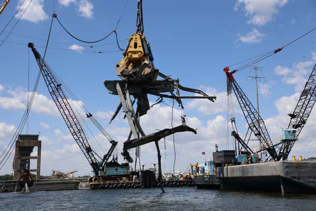 A floating crane equipped with a hydraulic grabber snags a 90-ton piece of wreckage from the Fort McHenry Federal Channel on June 7, 2024. 