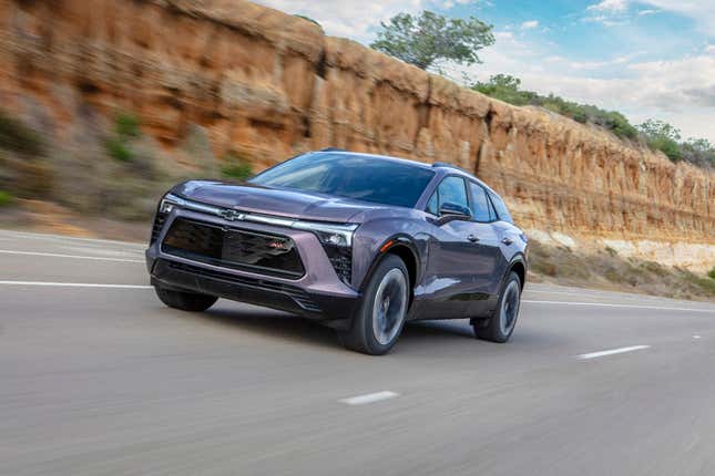 A purple-ish grey gunmetal Blazer driving by some cliffs