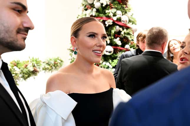 Scarlett Johansson wearing a black dress with white sleeves talking to a group of people