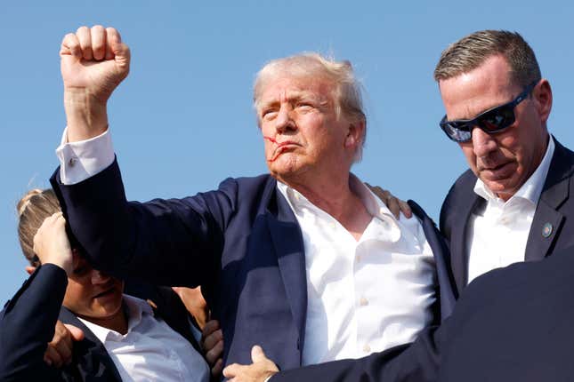 Republican presidential candidate former President Donald Trump pumps his fist as he is rushed offstage during a rally on July 13, 2024 in Butler, Pennsylvania. Butler County district attorney Richard Goldinger said the shooter is dead after injuring former U.S. President Donald Trump, killing one audience member and injuring another in the shooting.