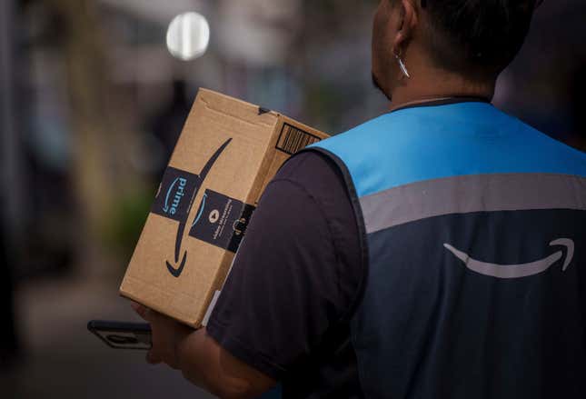 Amazon Prime delivery man wearing vest with Amazon logo and holding package with Amazon prime tape