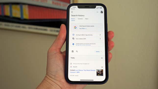 A photo of a person holding an iPhone up with the Google Search app opened to the Search history settings 