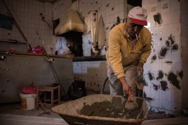 A man patches up the bullet holes in his bakery, which was used as a hideout by PKK-militants.