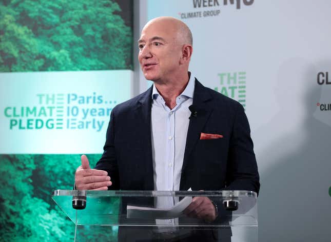 Jeff Bezos speaking at a clear podium with a sign behind him that says: "The Paris Climate 10 year Pledge Early"