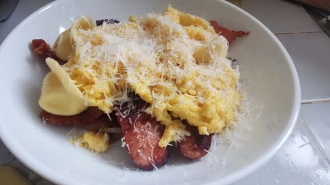 White bowl full of sliced meat, scrambled eggs, pasta, and cheese