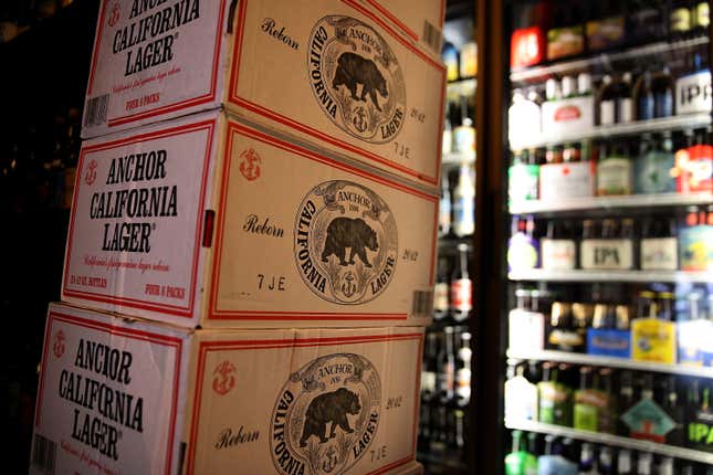 Stacks of Anchor California Lager branded beer next to a fridge.