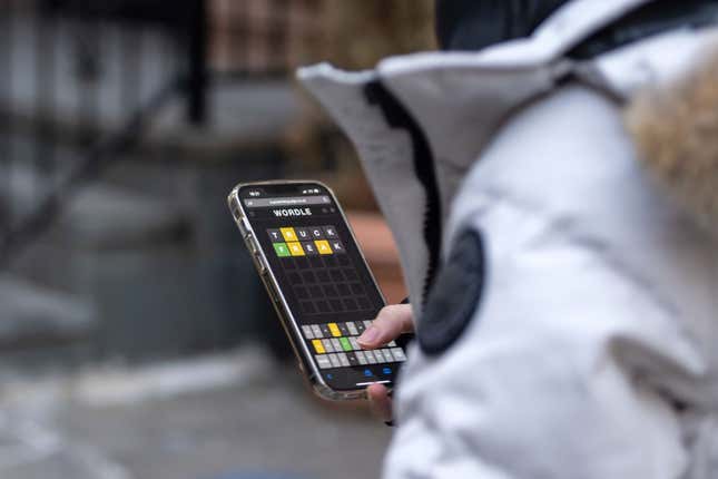 A person in a coat playing Wordle on a mobile phone.