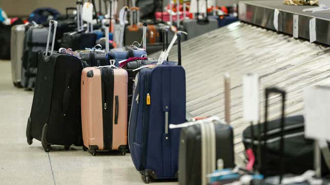 A photo of piles of bags waiting by a luggage carousel. 