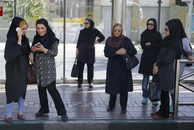 Women dressed in “hijab”wait for a bus in central Tehran, Iran.