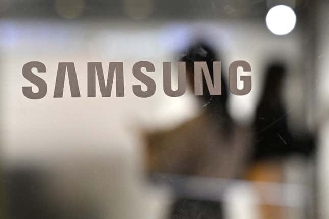 People walk past the Samsung logo displayed on a glass door at the company’s Seocho building in Seoul.