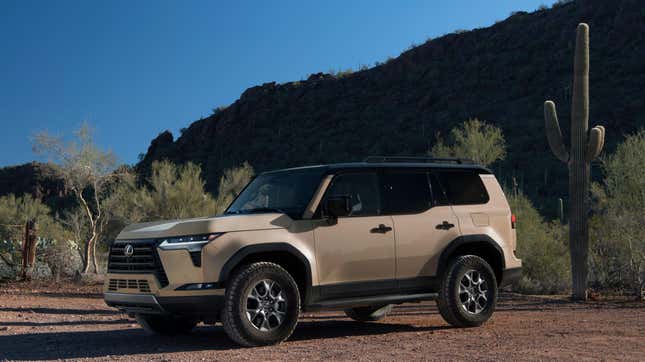 A tan GX parked in the desert in front of a tall cactus