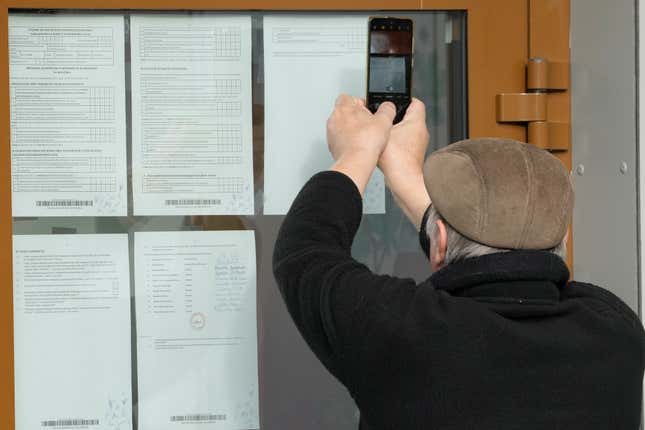 A man is checking and taking photos of the results of Sunday&#39;s parliamentary elections in Poland, in which more than 73% of eligible voters took part of whom majority voted for opposition parties, in Lomianki, near Warsaw, Poland, on Monday, Oct. 16, 2023. The full official results are expected Tuesday, but exit polls say that people have grown tired of the ruling conservative and divisive Law and Justice party, PiS.(AP Photo/Czarek Sokolowski)