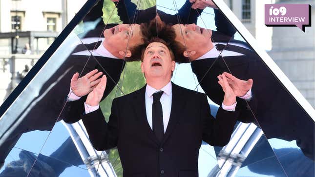 Sam Raimi looks up at multiple reflections of himself while standing in a mirrored pyramid.