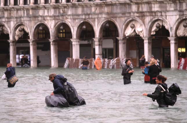 Passersby make their way through the floodwater, using rubbish sacks to keep their belongings dry.