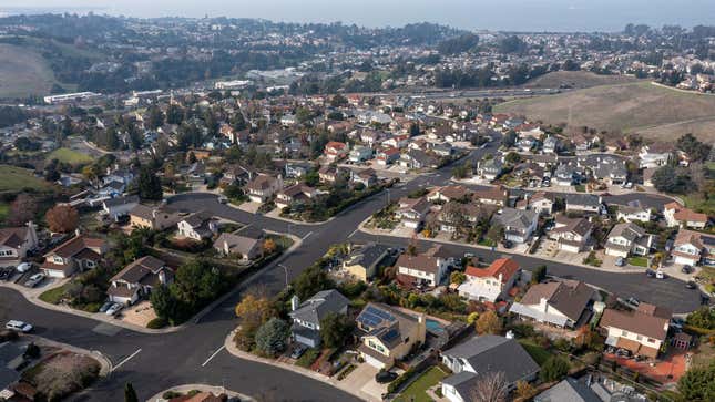 An aerial shot of homes in California on rolling hills near the sea.