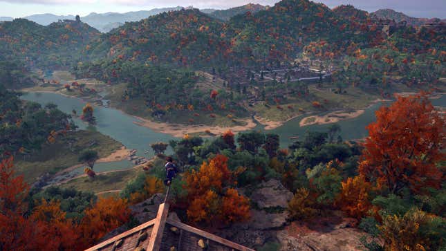 A screenshot of Assassin’s Creed Shadows. Naoe is on top of a building, looking out at a vast mountainous autumn landscape.