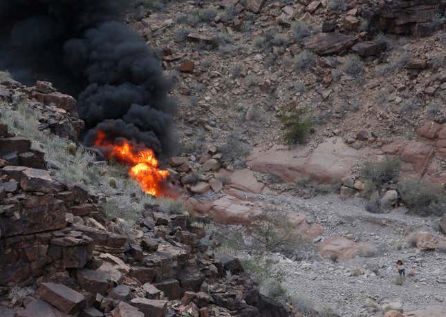 FILE - A survivor, lower right, walks away from the scene of a deadly tour helicopter crash along the jagged rocks of the Grand Canyon, Feb. 10, 2018, in Arizona. On Friday, Jan. 5, 2024, a Nevada judge approved a $100 million cash settlement to the parents of a British tourist who was among five killed — including his newlywed wife— when the helicopter crashed and burst into flames in the Grand Canyon in 2018. (Teddy Fujimoto via AP, File)