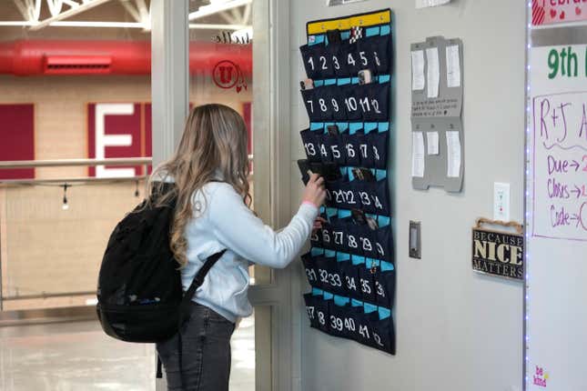 FILE - A ninth grader places her cellphone in to a phone holder as she enters class at Delta High School, Friday, Feb. 23, 2024, in Delta, Utah. Most schools have policies regulating student cellphone use at school. But the reality is kids don’t always follow the rules and schools enforce them sporadically. (AP Photo/Rick Bowmer, File)