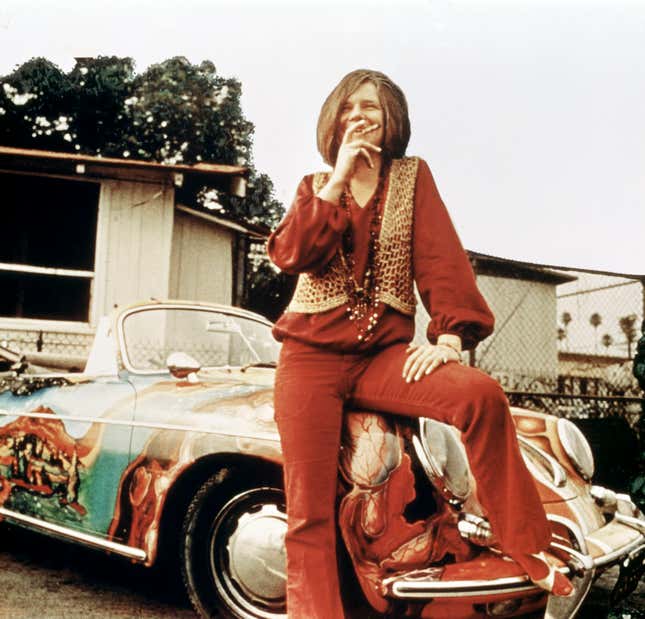 A vintage photo of Janis Joplin sitting on the front fender of her custom painted Porsche 356C
