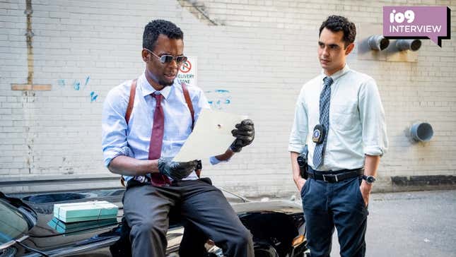Spiral: From the Book of Saw's Chris Rock examines a piece of paper while sitting on a car, Max Minghella looks on.