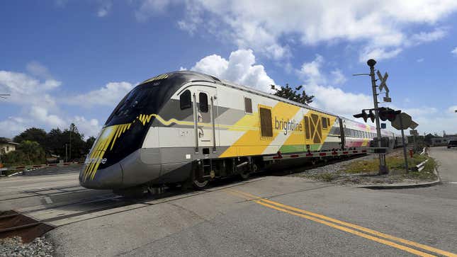 A photo of a Brightline train crossing a road. 