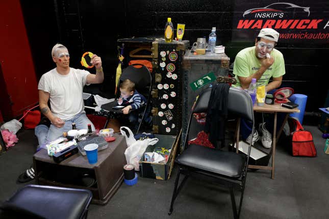 Ringling Bros. boss clown Sandor Eke, left, and Ivan Vargas put on makeup as Eke’s 2-year-old son Michael watches videos on a phone before a performance, May 5.