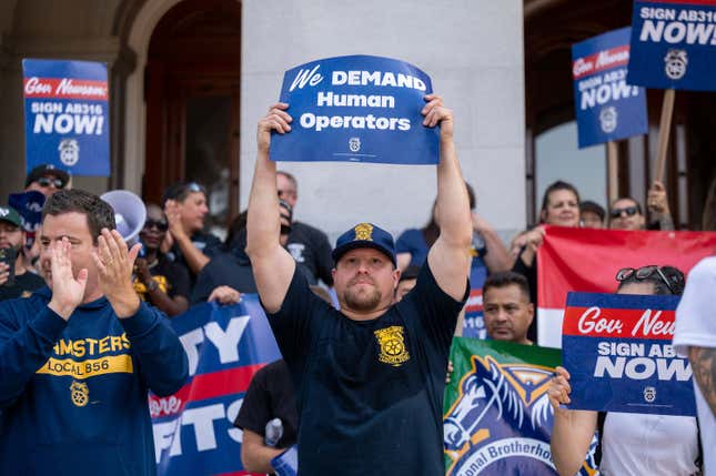 FILE- Teamsters union members hold signs urging Gov. Gavin Newsom to sign Assembly Bill 316, which would require in-person human supervision of self-driving vehicles weighing over 10,000 pounds, at the state Capitol in Sacramento, Calif., on Tuesday, Sept. 19, 2023. Gov. Gavin Newsom has vetoed a bill Friday, Sept. 22, 2023, that would have required human drivers to be onboard self-driving trucks, a measure that union leaders and truck drivers said would save hundreds of thousands of jobs. There are about 200,000 commercial truck drivers in California, according to Teamsters officials. (Paul Kitagaki Jr./The Sacramento Bee via AP, File)