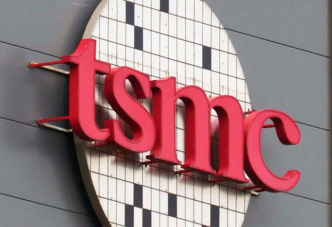 close up of tsmc letters in red on a circle with grids representing a chip wafer displayed at a factory