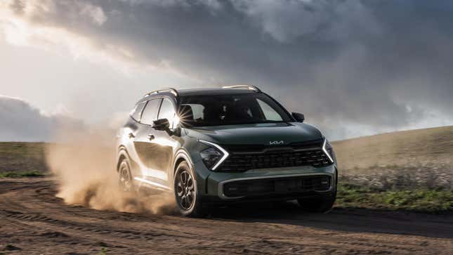 A blue-gray Kia Sportage driving through dirt